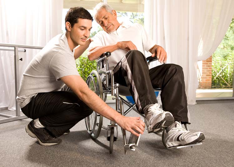 Pfleger hilft älterem Mann in den Rollstuhl