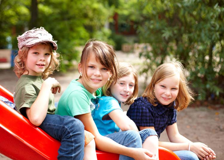 Kinder sitzen zusammen auf Rutsche © Christian Schwier - Fotolia.com Kinder sitzen zusammen auf Rutsche