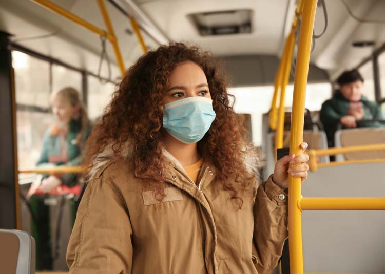Frau mit einer Gesichtsmaske fährt Bus © New Africa - stock.adobe.com Frau mit einer Gesichtsmaske fährt Bus