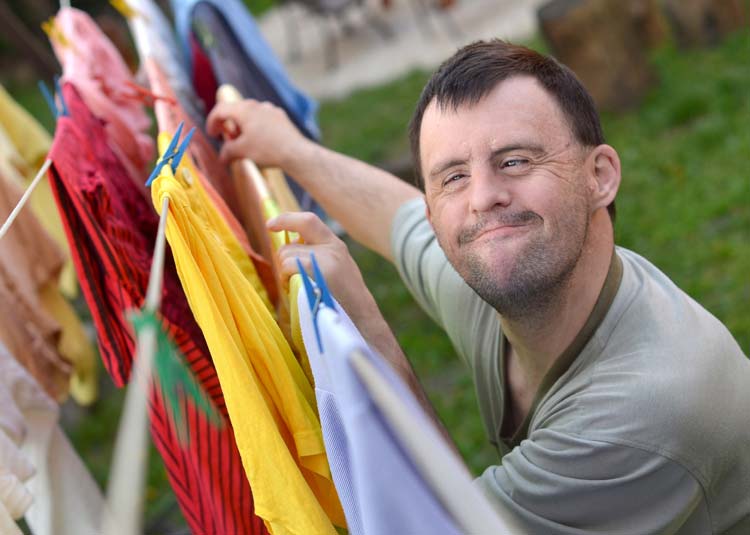 Mann mit Behinderung hängt Wäsche auf © muro - Fotolia.com Mann mit Behinderung hängt Wäsche auf