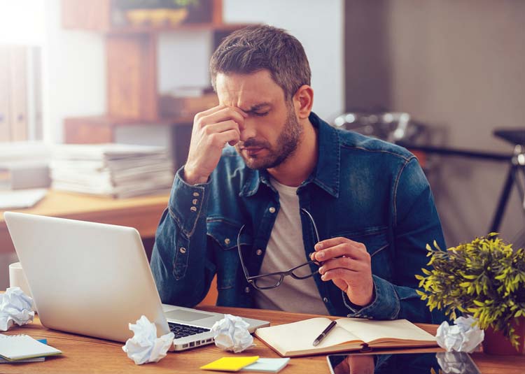 Überforderter Mann am Schreibtisch © gstockstudio - Fotolia.com Überforderter Mann am Schreibtisch